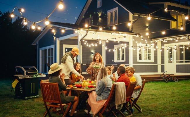 family and friends eating outside in backyard in the summer