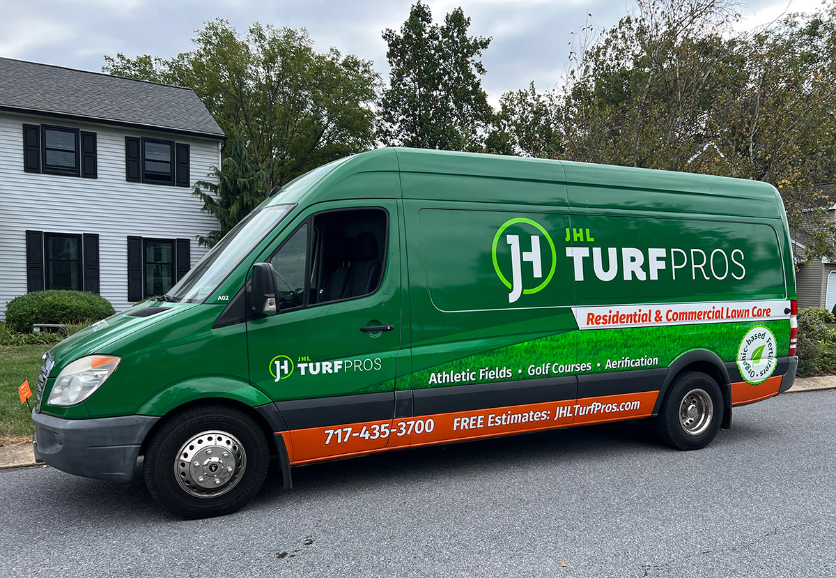 JHL Turf Pros lawn care van in front of a residential house for a lawn treatment